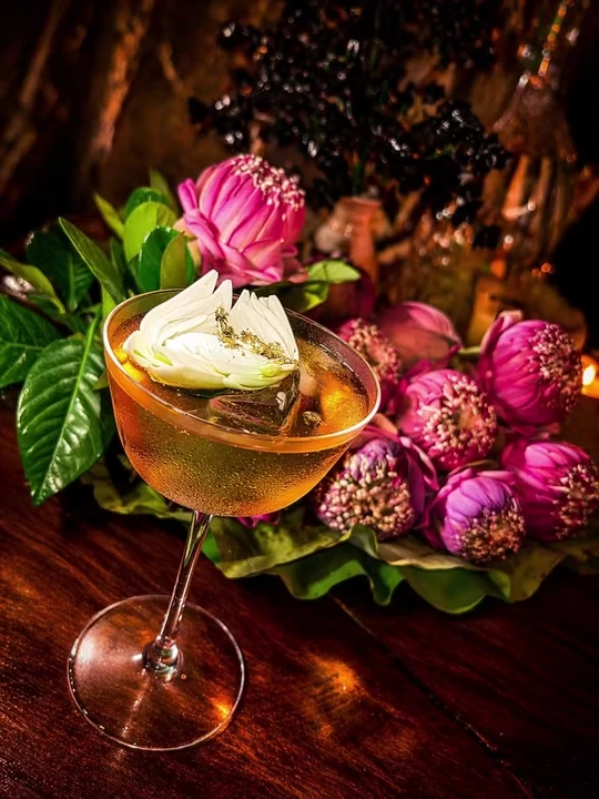 Floral cocktails surrounded by pink lotus flowers and drifting mist.