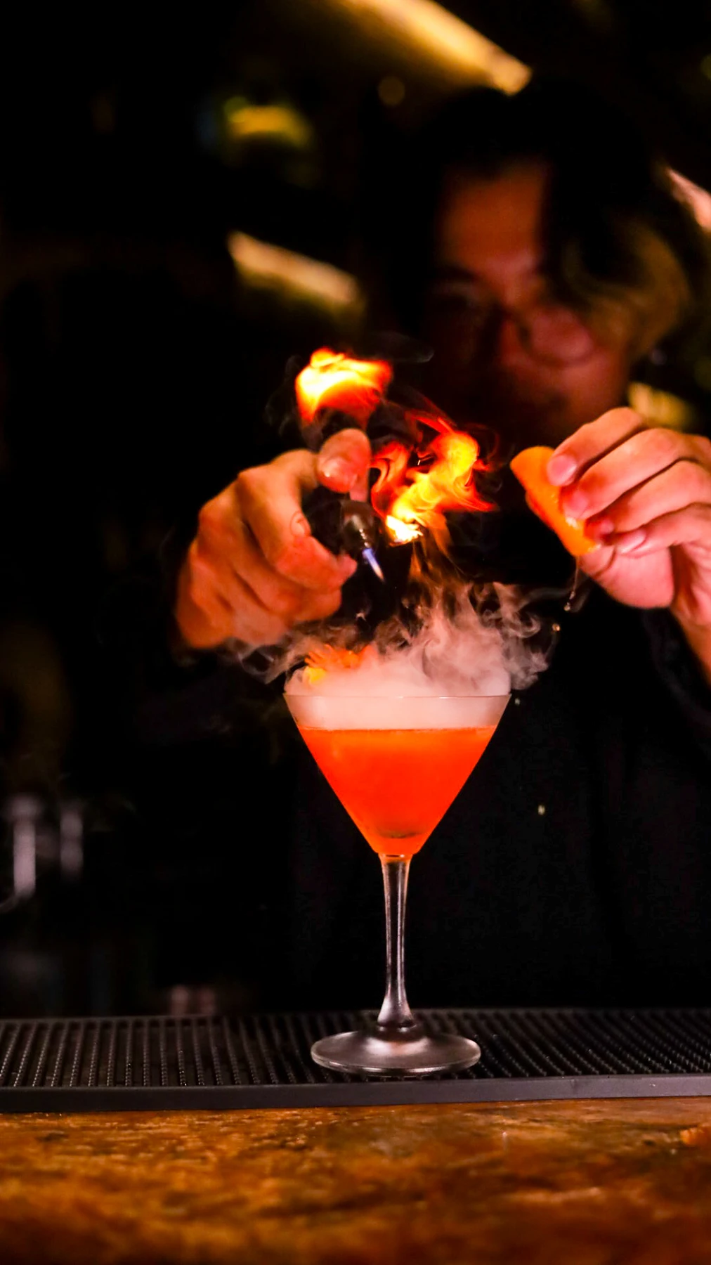 A Root Bar bartender finishing a cocktail with a flame