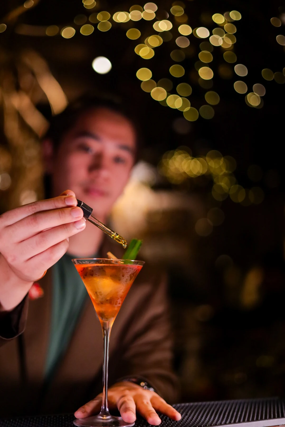 A bartender placing the finishing garnish on a cocktail